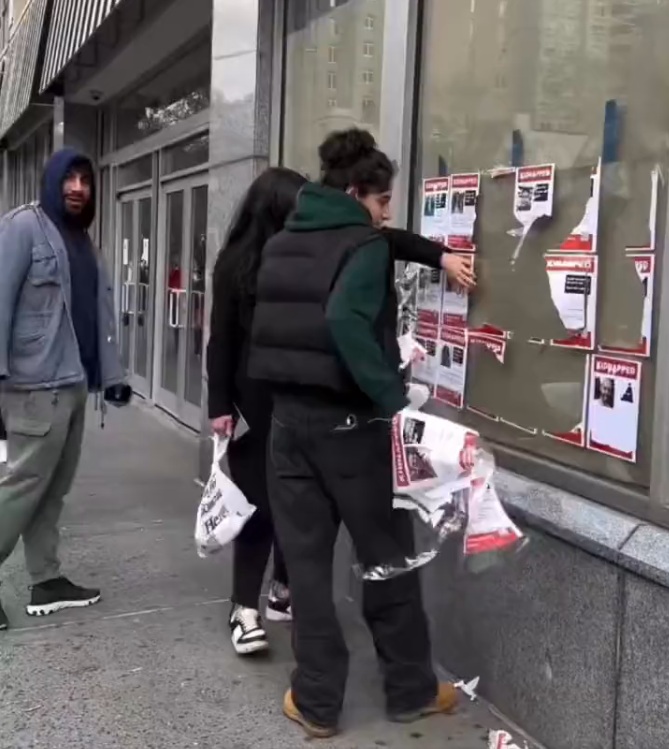 Young people tearing down posters memorializing hostages